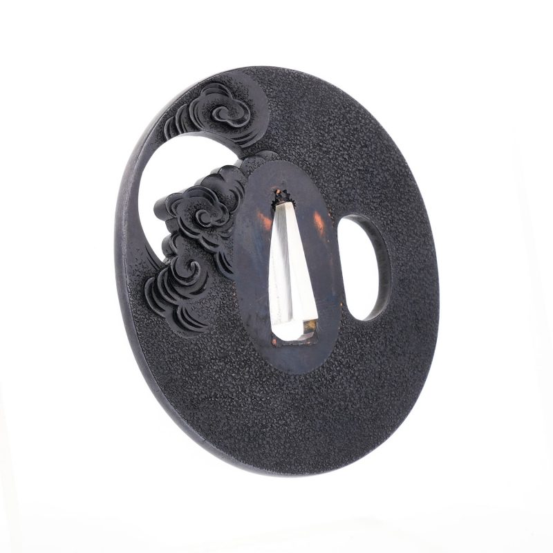 On a richly patinated shakudō ground, hammered with tsuchime to evoke the image of drifting clou ...
