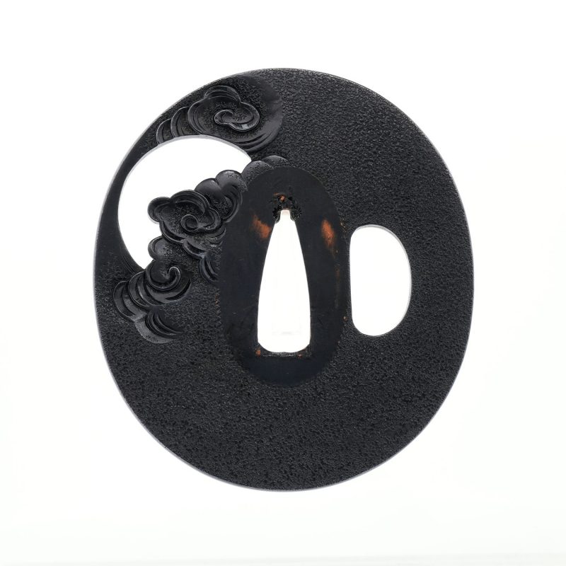On a richly patinated shakudō ground, hammered with tsuchime to evoke the image of drifting clou ...