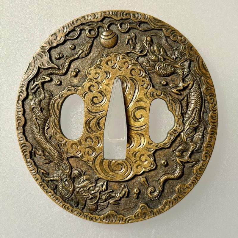 （一）宝珠七宝雲龍図鐔 銘 平戸住 国重造
竪丸形 真鍮石目地 鋤出彫 鋤残耳

→ (1) Tsuba with a desi ...